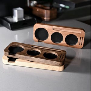 May include: Wooden desk organizers in various shades of brown. Each organizer features circular cutouts with black mesh and a slot for holding items. The organizers are rectangular and have a minimalist design.
