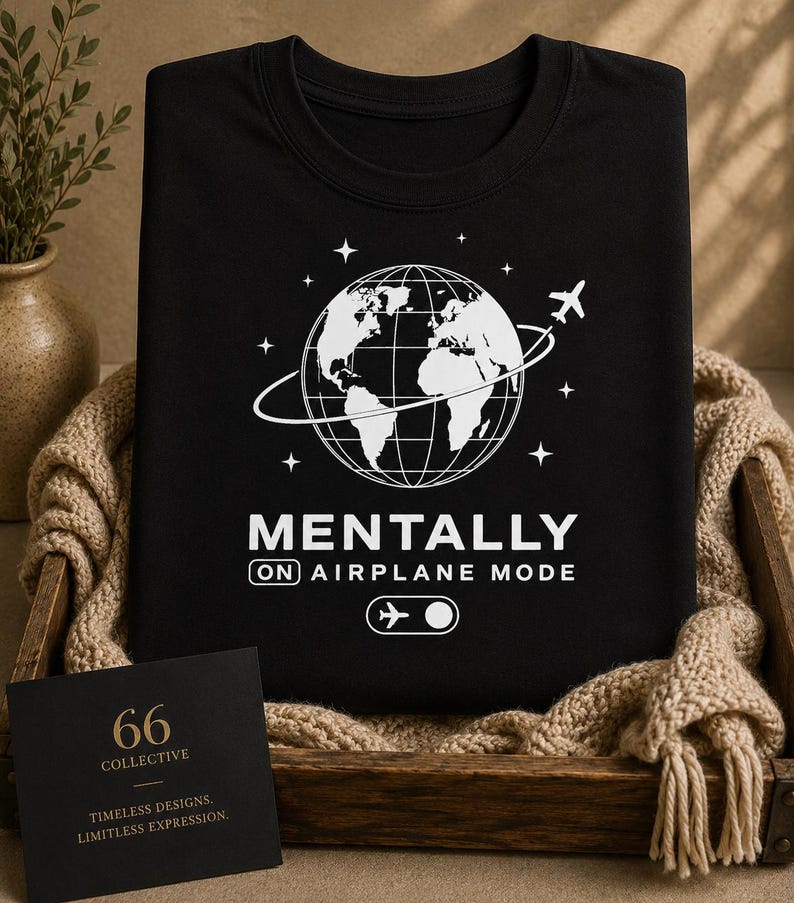 May include: Black t-shirt featuring a white globe, airplane, and stars graphic. The text says "MENTALLY ON AIRPLANE MODE." A small card in the lower left corner reads "66 COLLECTIVE" and "TIMELESS DESIGNS. LIMITLESS EXPRESSION."