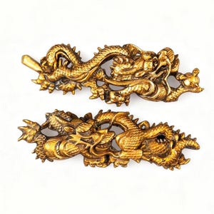 May include: Two ornate, golden dragon sculptures. Each dragon is intricately detailed with scales, claws, and a flowing body. The dragons are positioned horizontally against a white background, showcasing their detailed craftsmanship.
