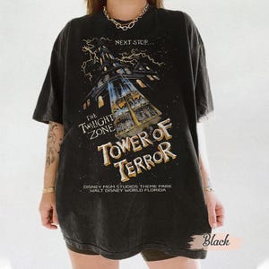 May include: Black graphic t-shirt featuring the text "THE TWILIGHT ZONE TOWER OF TERROR" with an illustration of a tall building and lightning. The shirt also includes the text "DISNEY MGM STUDIOS THEME PARK WALT DISNEY WORLD FLORIDA".