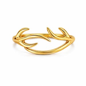 May include: A gold-colored ring with a unique antler design. The ring features a smooth, polished finish and a curved, open design. The antler-like elements extend outwards, creating a distinctive and elegant piece of jewelry.