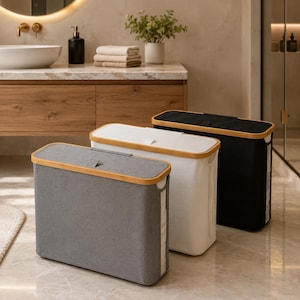 May include: Three rectangular laundry hampers with fabric bodies and bamboo lids. The hampers are arranged in a row, featuring a grey hamper in the front, a white hamper in the middle, and a black hamper in the back, each with a small fabric tab.