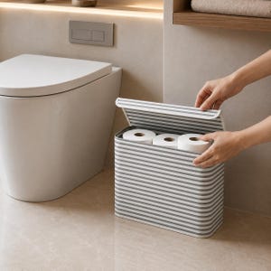 Op de afbeelding: Een rechthoekige opbergbak met een scharnierend deksel, voorzien van een patroon van horizontale grijze en witte strepen. De container is ontworpen om meerdere rollen toiletpapier in op te bergen, die zichtbaar zijn in het open vak.