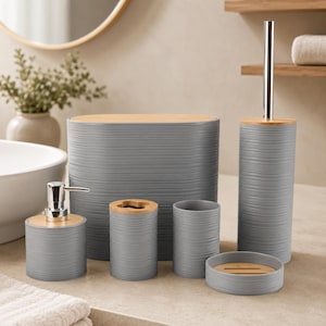 May include: A six-piece bathroom accessory set featuring a gray ribbed texture and light wood accents. The set includes a waste bin, a soap dispenser with a silver pump, a toothbrush holder, a tumbler, a soap dish, and a toilet brush holder.