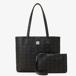 Puede incluir: Juego de bolso tote y neceser a juego de color negro. El bolso tote tiene asas largas y un dise&ntilde;o estructurado. Ambas piezas presentan un patr&oacute;n de logotipo repetido. El neceser tiene una correa de mu&ntilde;eca y cierre de cremallera. El conjunto es de material duradero.