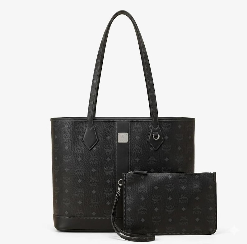 Puede incluir: Juego de bolso tote y neceser a juego de color negro. El bolso tote tiene asas largas y un dise&ntilde;o estructurado. Ambas piezas presentan un patr&oacute;n de logotipo repetido. El neceser tiene una correa de mu&ntilde;eca y cierre de cremallera. El conjunto es de material duradero.