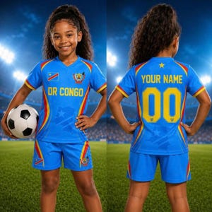 Könnte beinhalten: Ein blaues Fußballtrikot mit der Aufschrift DR CONGO, der Nationalflagge und einem Löwenemblem auf der Vorderseite. Auf der Rückseite stehen der Text YOUR NAME und die Nummer 00 in Gelb. Das Set besteht aus einem Trikot und einer kurzen Hose.
