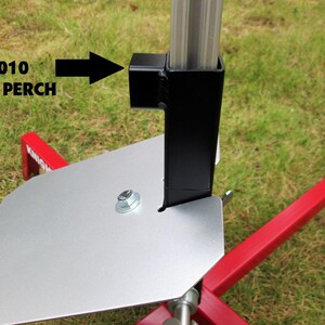 May include: A close-up of a black metal bracket attached to a silver metal plate. The bracket is labeled "RP-1010 RAIL PERCH".