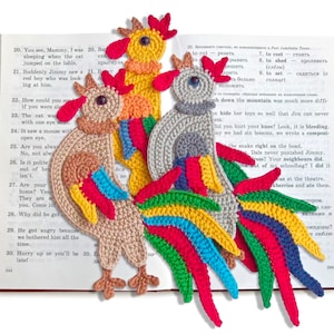 Peut inclure: Quatre marque-pages en forme de coq crochetés dans différentes couleurs, dont le rouge, le jaune, le vert et le bleu. Les marque-pages sont placés sur un livre ouvert.