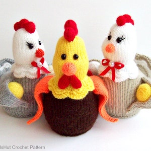 Pode incluir: Três brinquedos de frango de malha. Um é amarelo com um corpo de ovo castanho, outro é branco com um corpo cinzento e outro é branco com um corpo castanho. Todos têm cristas e bicos vermelhos.