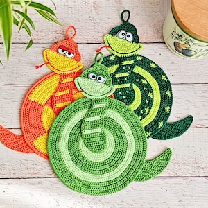 May include: Three crocheted snake pot holders in green, orange, and yellow. The snakes are curled up in a circle and have googly eyes.