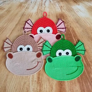 May include: Three crocheted pot holders shaped like cartoon fish with smiling faces. The fish are red, beige, and green.