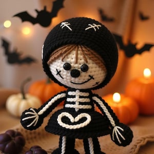 Op de afbeelding: Een gehaakte skeletpop met een zwarte hoed met witte stiksels. De pop is omringd door pompoenen en vleermuizen, wat een Halloween-thema creëert.