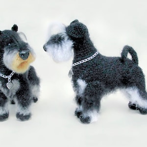 May include: Two crocheted miniature schnauzer dogs, one black and white with a silver chain collar and the other black and white with a silver chain collar and a heart charm.
