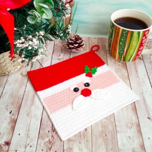 May include: A crocheted Santa Claus face with a red hat, white beard, and pink cheeks. The face is on a white and red crocheted square.