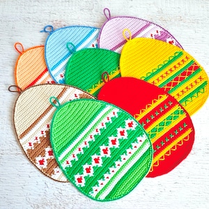 Może przedstawiać: Zestaw dziewięciu dzianych uchwytów do garnków w kształcie jajka w różnych kolorach, w tym zielonym, czerwonym, żółtym, pomarańczowym, fioletowym i niebieskim. Uchwyty do garnków mają różne wzory, w tym paski, romby i krzyżyki.