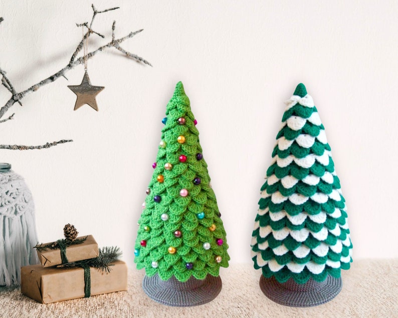 May include: Two crocheted Christmas trees, one green with colorful beads and one green and white, stand on a white background.