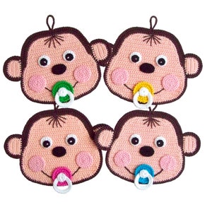 May include: Four crocheted baby faces with dummies. Each face is a different colour: pink, brown, yellow, and blue. The faces are all smiling and have brown yarn hair.