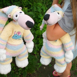 May include: Two plush pink and white striped toy animals wearing pyjamas. One is being held by a person, the other is standing on its own. Both have a mouse embroidered on their shirts.