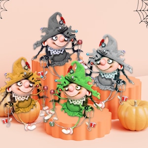 Op de afbeelding: Vier gehaakte gnoom-ornamenten met puntige hoeden, elk met een andere outfit: grijs, groen, geel en rood. De gnomes zitten op oranje pompoenen en zijn versierd met kralen en belletjes.