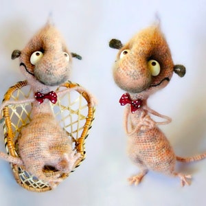 May include: Two crocheted plush toys with large eyes and a bow tie. One is sitting in a wicker chair, the other is standing.