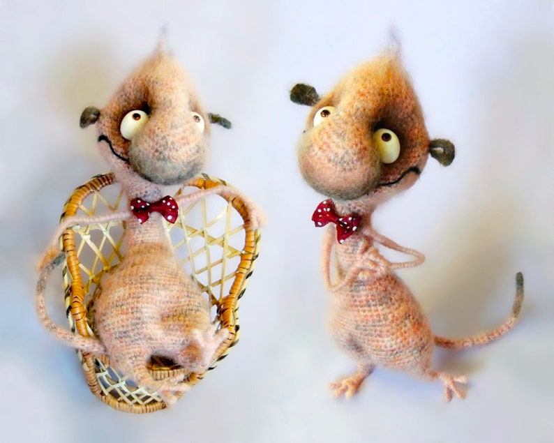 May include: Two crocheted plush toys with large eyes and a bow tie. One is sitting in a wicker chair, the other is standing.