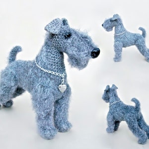 May include: A gray crocheted miniature schnauzer dog toy with a silver chain and heart charm. The toy is shown in three different poses.