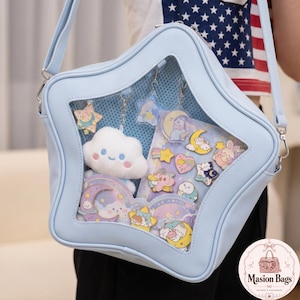 May include: A light blue star-shaped crossbody bag with a clear front panel, showcasing a cloud plushie and various celestial-themed charms. The bag has a shoulder strap and a decorative design.