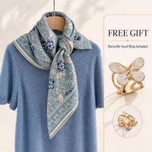 May include: A light blue short-sleeved sweater with a blue, white, and tan floral patterned scarf tied at the neck. A gold-toned butterfly scarf ring with white enamel detailing is displayed separately, labeled with the text FREE GIFT.
