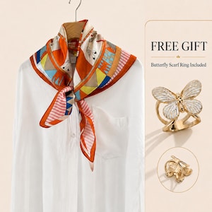 May include: A square silk scarf featuring a geometric pattern in orange, blue, yellow, and white, tied around the neck of a white button-down shirt. A gold-toned metal scarf ring shaped like a butterfly with white enamel wings is also shown.