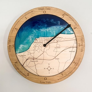 May include: A circular wooden tide clock featuring a map of Whitstable, Kent. The clock face has a blue and white resin ocean design. The clock hands show the tide level, with text indicating high and low tide.