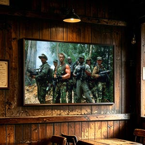 May include: A rectangular framed wall art print depicting a group of six soldiers in camouflage uniforms standing in a dense jungle setting, each carrying military-style rifles and gear, with a dark wooden wall background and a hanging light fixture.