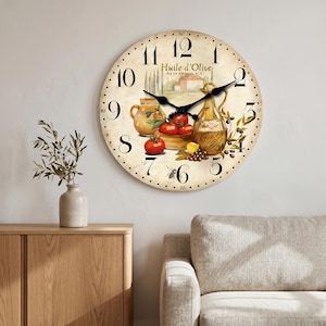 May include: A round wall clock with a cream-coloured face featuring black Arabic numerals and a decorative illustration of a glass oil cruet, red tomatoes, and a ceramic pitcher. The text Huile d'Olive Aix en provence AOC is printed.