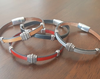 May include: Four leather bracelets with magnetic clasps and silver-toned bead accents. The bracelets are in red, tan, black, and grey.