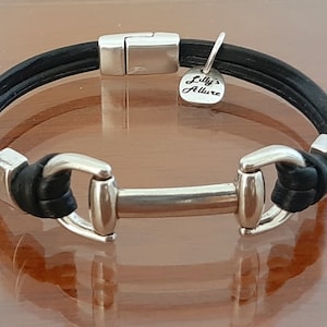 May include: Black leather bracelet with a silver equestrian bit charm and a silver tag that reads "Lilly's Allure".