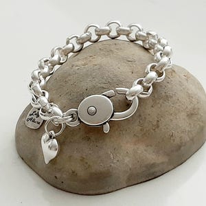 Könnte beinhalten: Ein silbernes Kettenarmband mit einem Herz-Anhänger und einem Karabinerverschluss. Der Anhänger trägt die Gravur "Lily Alice".