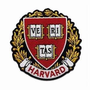 May include: An embroidered patch featuring the Harvard University crest. The design includes a red shield with three open books displaying the text VERI TAS in black, surrounded by a gold laurel wreath and a white banner with HARVARD in red.