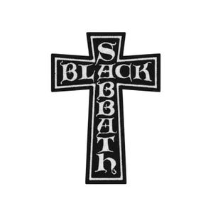 May include: Black and white embroidered patch in the shape of a cross. The cross features the words "BLACK SABBATH" in a gothic font. The patch has a black border and is likely designed to be ironed or sewn onto clothing or accessories.
