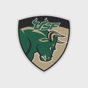 Puede incluir: Parche bordado con un toro verde con las letras "USF" en verde y blanco. El parche tiene forma de escudo con la parte superior negra, el centro beige y el borde blanco. El toro mira hacia la derecha.