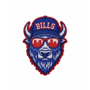 Op de afbeelding: Geborduurde patch met een blauwe buffel die een blauwe baseballpet draagt met het woord "BILLS" in het wit. De buffel heeft een rode zonnebril met een skyline-ontwerp. De patch heeft een rode rand.