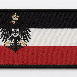 Op de afbeelding: Geborduurde patch met de vlag van het Duitse Rijk. De rechthoekige patch heeft een zwarte rand en is verdeeld in drie horizontale strepen: zwart, wit en rood. Een gedetailleerd adelembleem staat aan de linkerkant.