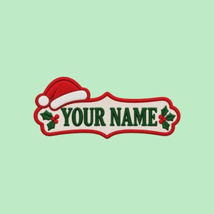 May include: A rectangular embroidered patch with a scalloped border featuring the text YOUR NAME in dark green. The design includes a red and white Santa hat on the left and green holly leaves with red berries on both sides.