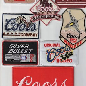 Peut inclure: Collection de patchs brodés avec le logo Coors et des motifs associés. Les patchs incluent les mots "Banquet", "Cowboy", "Silver Bullet" et "Rodeo". Les couleurs sont le rouge, le blanc, le bleu et le noir.