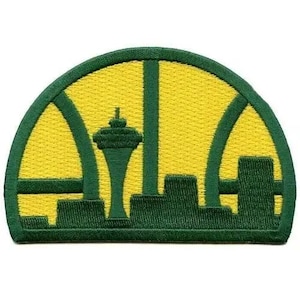 May include: Embroidered patch featuring a yellow and green design. The patch depicts a cityscape with a prominent tower, set within a green arch. The patch has a textured appearance, with a green border.