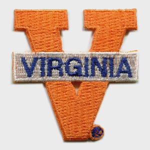 May include: Embroidered patch featuring a large orange "V" shape with the word "VIRGINIA" in blue letters on a white background. The patch has a textured appearance and a small blue accent at the bottom.