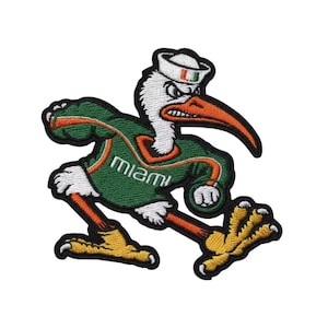 Puede incluir: Parche bordado con una mascota de pájaro estilizada en verde, naranja, blanco y negro. El pájaro lleva un gorro de marinero y una camiseta verde con la palabra "Miami". El parche tiene un borde negro.
