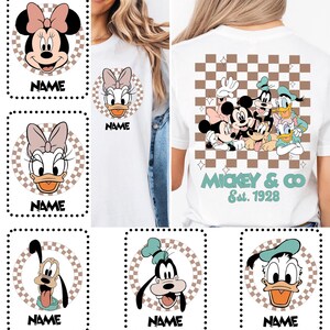 Puede incluir: Una camiseta blanca con un gr&aacute;fico en la espalda de Mickey Mouse, Minnie Mouse, Donald Duck, Daisy Duck, Goofy y Pluto sobre un patr&oacute;n de cuadros marr&oacute;n y blanco con el texto Mickey & Co Est. 1928. El frente muestra un personaje en un c&iacute;rculo.