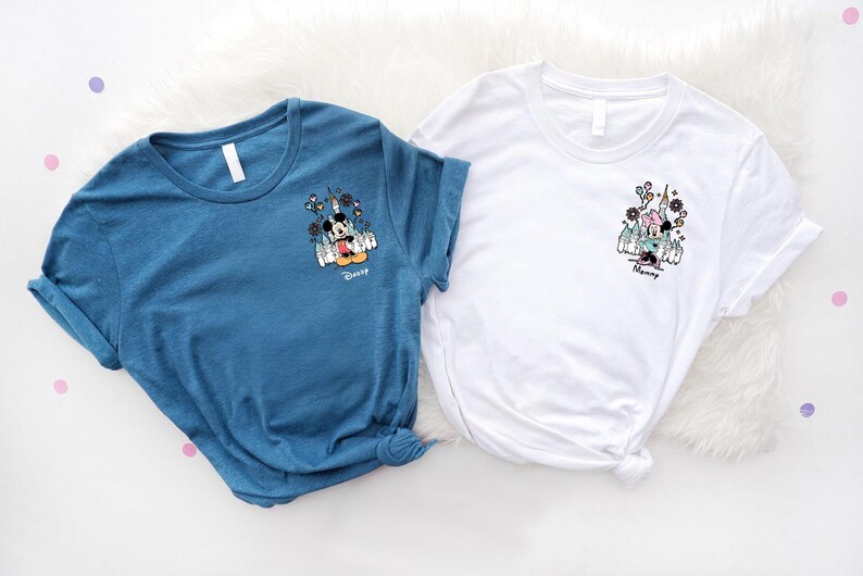 May include: A blue t-shirt and a white t-shirt, each featuring a small graphic on the left chest. The blue shirt displays Mickey Mouse with the text "Daddy" below, while the white shirt shows Minnie Mouse with the text "Mommy" below.
