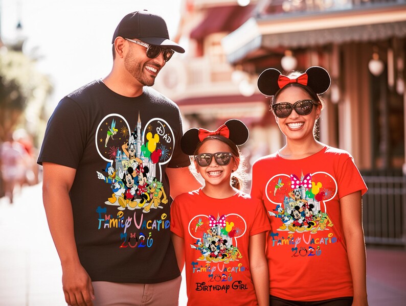 May include: A black t-shirt with a Mickey Mouse silhouette graphic containing Disney characters and the text Family Vacation 2026, and two red t-shirts with similar graphics, one featuring the additional text Birthday Girl below the main design.