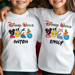 May include: White t-shirts with a colorful "Disney World 2026" design. The design includes Mickey and Minnie Mouse heads, and the names "Anton" and "Emily" are printed below the numbers.
